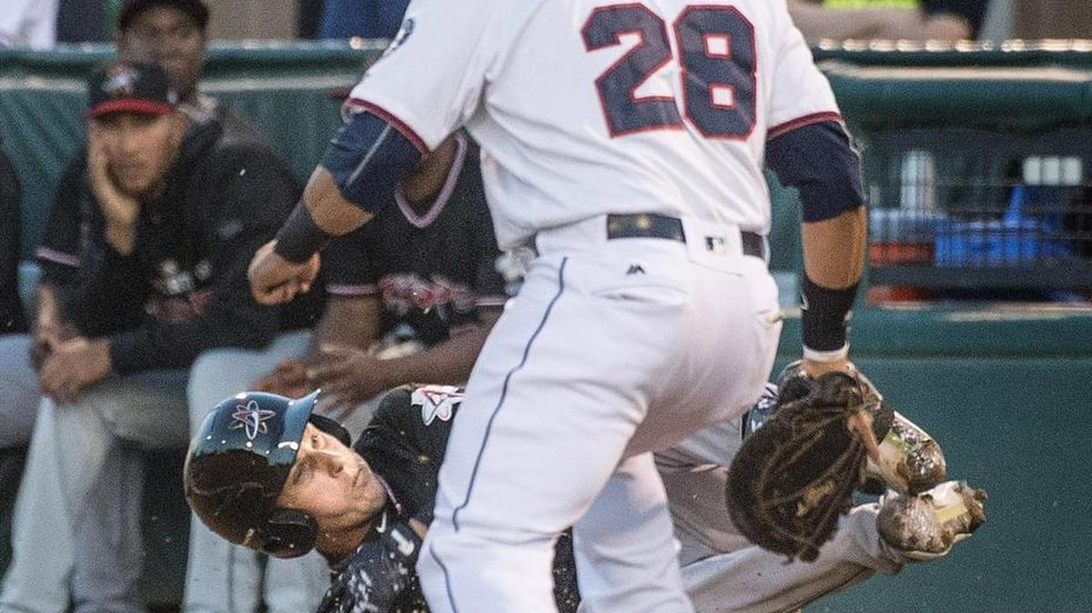Albuquerque Isotopes's Dustin Garneau tumbles over first base on a wild throw to first basemen Efren Navarro by Rainer's shortstop Chris Taylor in the first inning Thursday 04/07/16 during the Tacoma Rainier's season opener against the Albuquerque Isotopes at Cheney Stadium. Both teams scored two runs in the first.