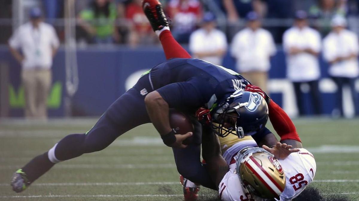 Seahawks quarterback Russell Wilson is pulled down awkwardly by the San Francisco 49ers’ Eli Harold on Sept. 25. Injuries to Wilson’s knee and ankle have hindered the Seahawks’ rushing attack this season.