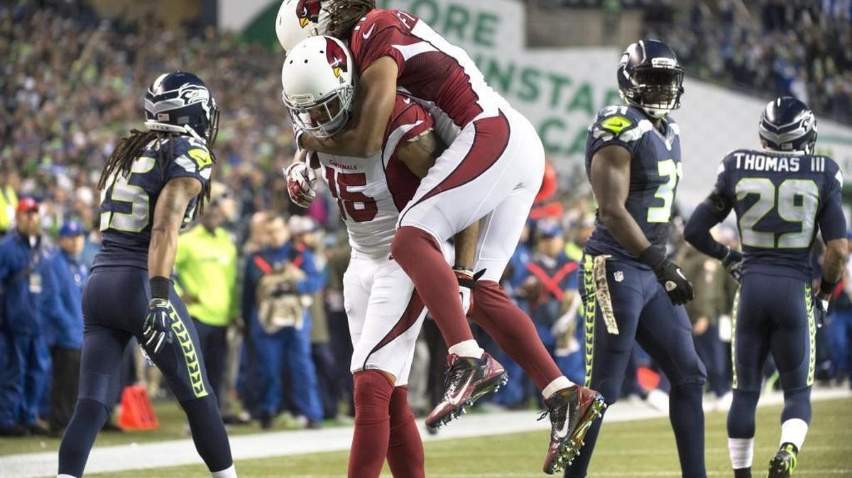 Cardinals wide receiver Michael Floyd is hugged by teammate Larry Fitzgerald following a long catch during Sunday night's NFL football game at CenturyLink Field in Seattle on Nov. 15, 2015.