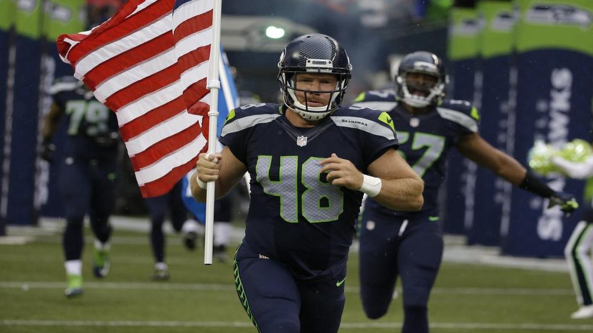 
Former Seahawks long snapper and military veteran Nate Boyer runs out of the tunnel Friday at CenturyLink Field with an American flag before the team’s exhibition opener against the Denver Broncos. Boyer was released by the Seahawks on Tuesday to make way for quarterback Jake Waters.
