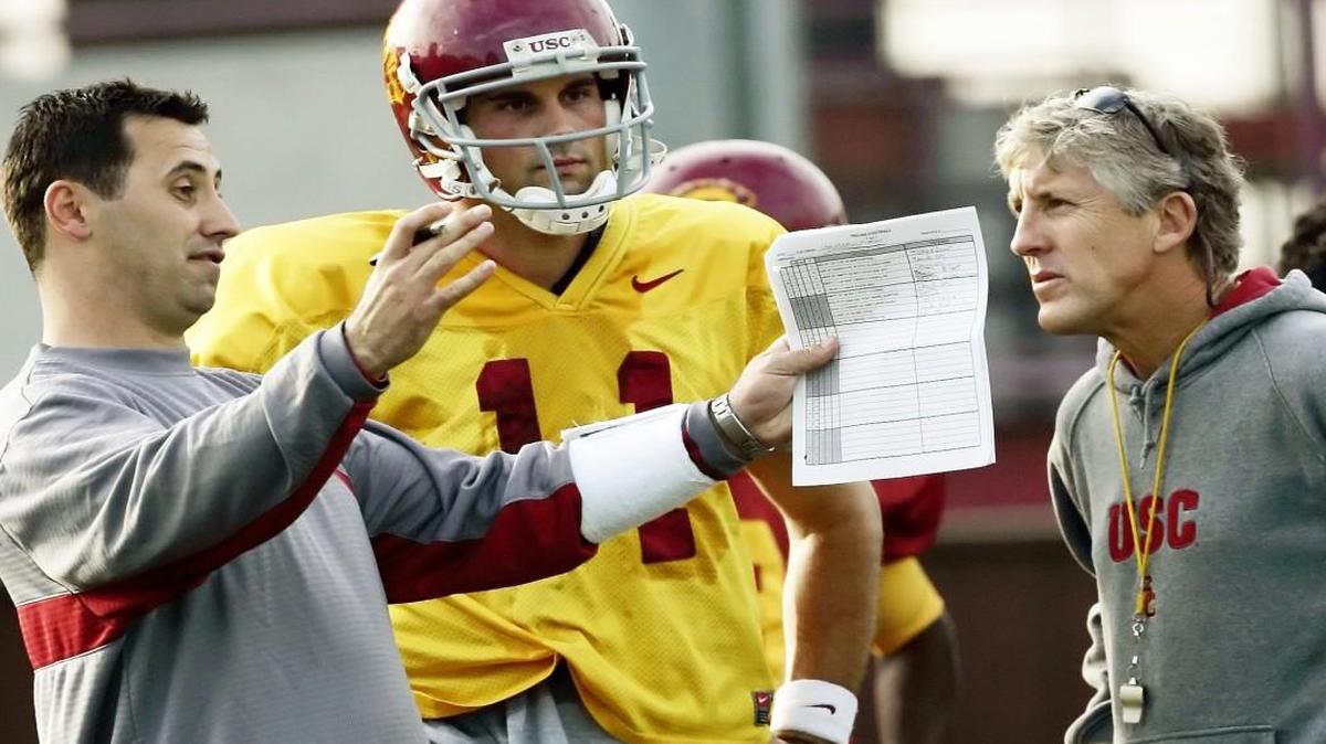 
Former USC coach Pete Carroll, right, talks to then-assistant head coach Steve Sarkisian as quarterback Matt Leinart looks on. Sarkisian was fired by USC as head coach Monday.
