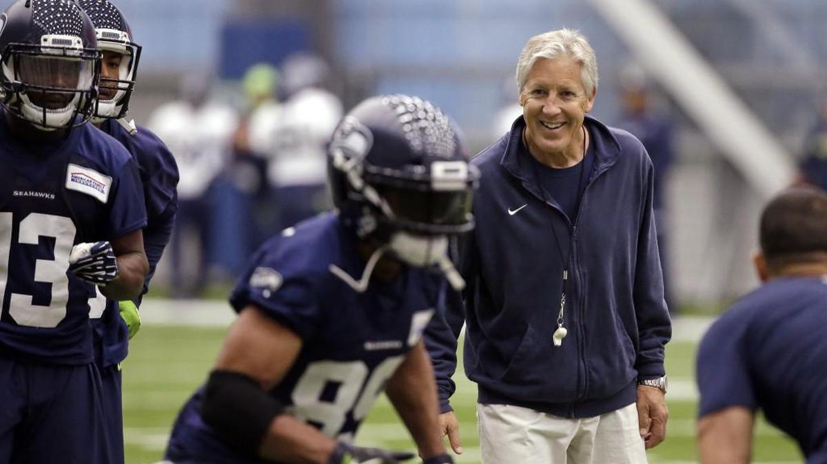Seattle Seahawks head coach Pete Carroll, right, smiles as he watches Doug Baldwin run a drill on Thursday, the last practice before training camp starts in July.