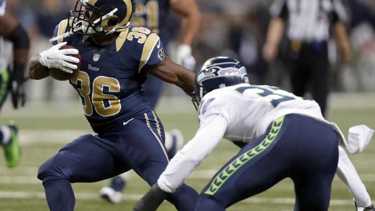 
Rams running back Bennie Cunningham, left, tries to elude Seahawks safety Dion Bailey, who was starting in place of holdout Kam Chancellor, on Sunday in St. Louis. Bailey would later allow a key touchdown pass.
