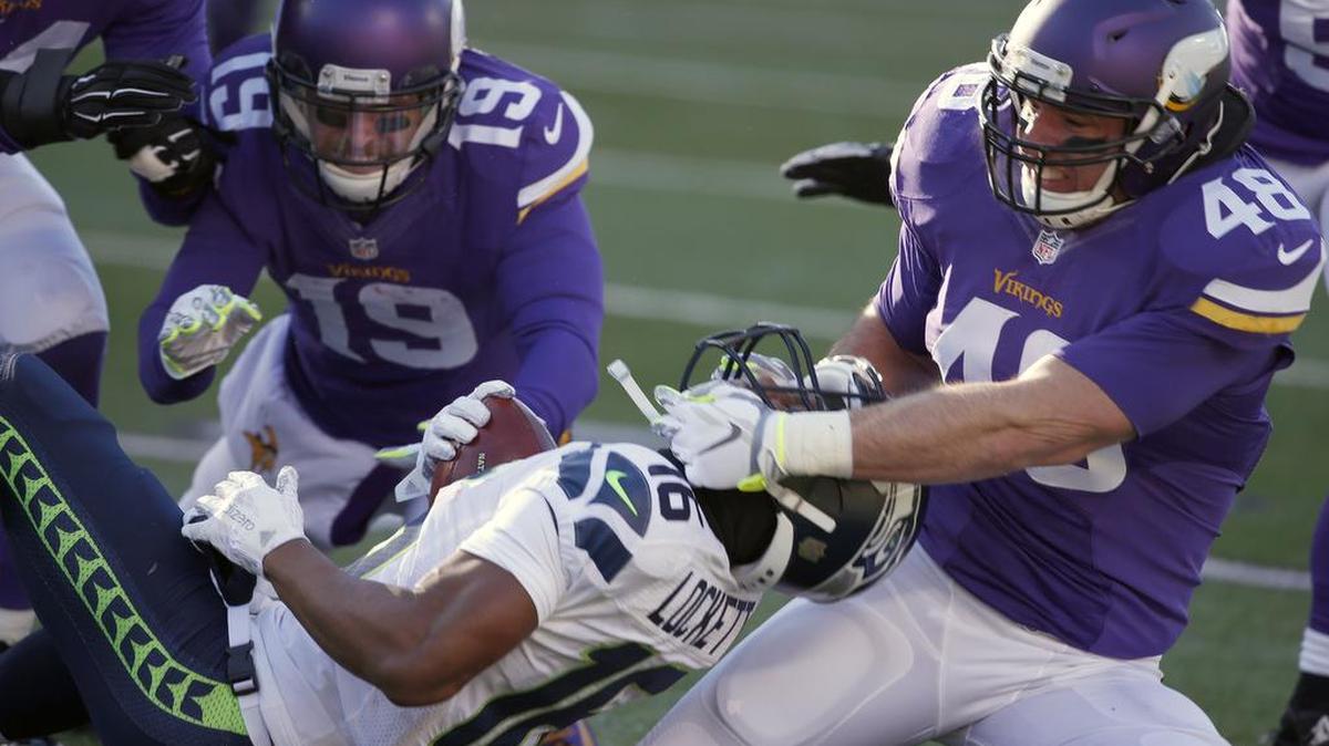 Minnesota’s Zach Line (48) pulls down Seattle’s Tyler Lockett by his helmet. Lockett was one of the Seattle players who decided against wearing sleeves in the cold.
