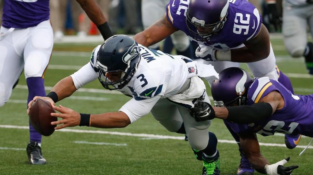 Seattle Seahawks quarterback Russell Wilson (3) dives for a eight-yard touchdown run as Minnesota Vikings cornerback Antone Exum (32) defensive tackle Tom Johnson (92) try to bring him down in the first half of an NFL football game Sunday, Dec. 6, 2015 in Minneapolis.