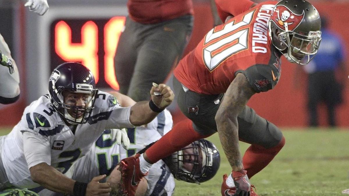 Tampa Bay Buccaneers free safety Bradley McDougald (30) slips an arm tackle by Seattle Seahawks quarterback Russell Wilson (3) and center Joey Hunt (53) after intercepting a pass by Wilson during the second half of an NFL football game in Tampa, Fla., Sunday, Nov. 27, 2016. The Buccaneers won 14-5.