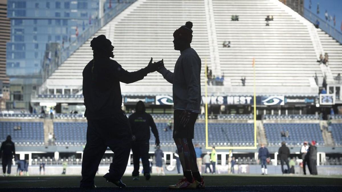 Seahawks running back Marshawn Lynch greets a 49ers player at midfield in Seattle on Sunday. Lynch tested his abdominal injury during these early warmups, but the injury kept him out of that game. It now has him in Philadelphia seeing a specialist.