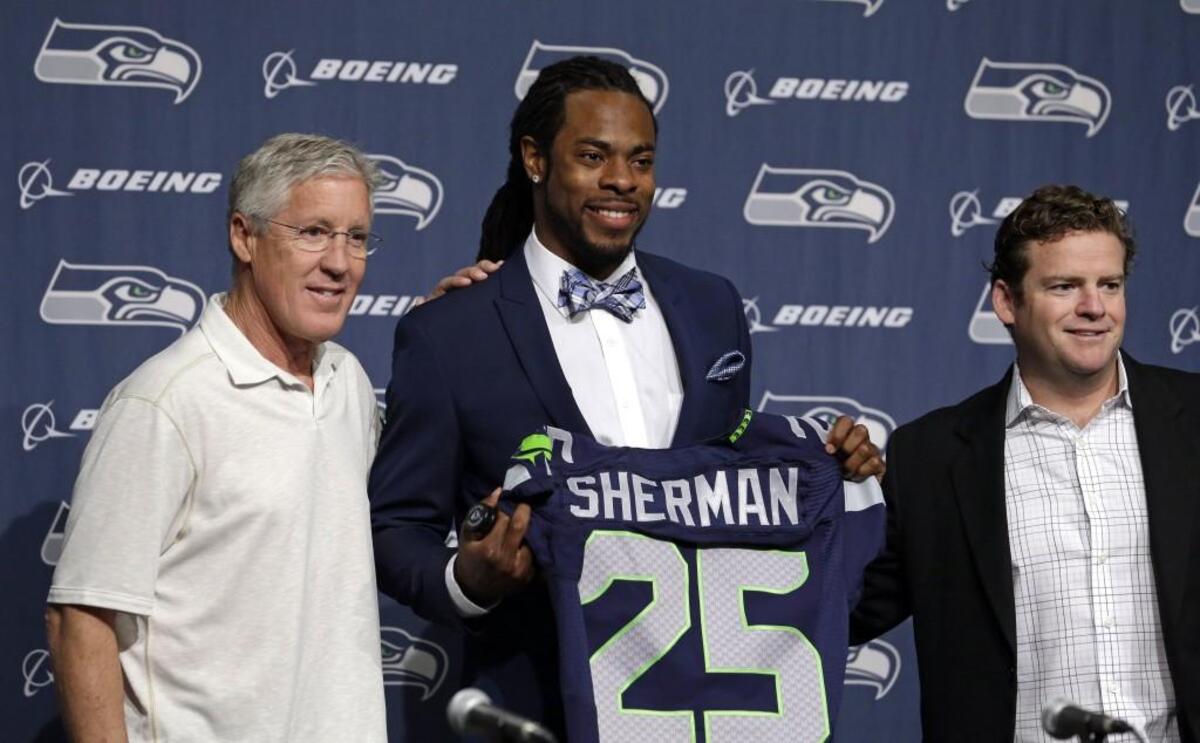 Seahawks coach Pete Carroll, three-time All-Pro cornerback Richard Sherman (center) and general manager John Schneider are in a different place now than they were when this photograph was taken in 2014 for Sherman signing a four-year contract extension.