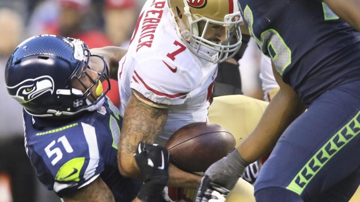 A familiar sight: 49ers quarterback Colin Kapernick going down against the Seahawks. General manager Trent Baalke said Wednesday at the NFL combine he expects the unhappy, healing Kaepernick to remain on San Francisco’s roster.