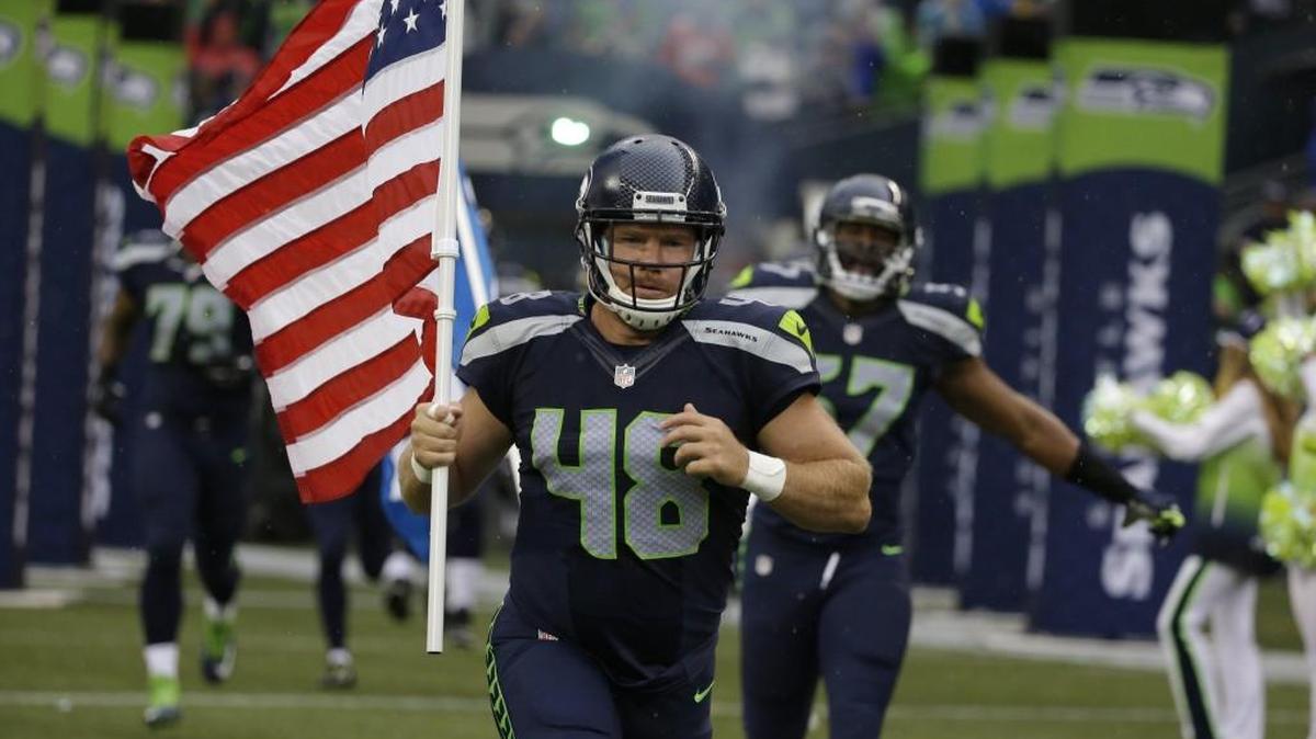Ex-Seahawks long snapper and former U.S. Army Special Forces Green Beret Nate Boyer runs out of the CenturyLink Field tunnel with a U.S. flag at the start of a preseason game against Denver on Aug. 14, 2015. Boyer will raise the Seahawks’ “12th Man” flag just before Monday night’s home game against Buffalo.