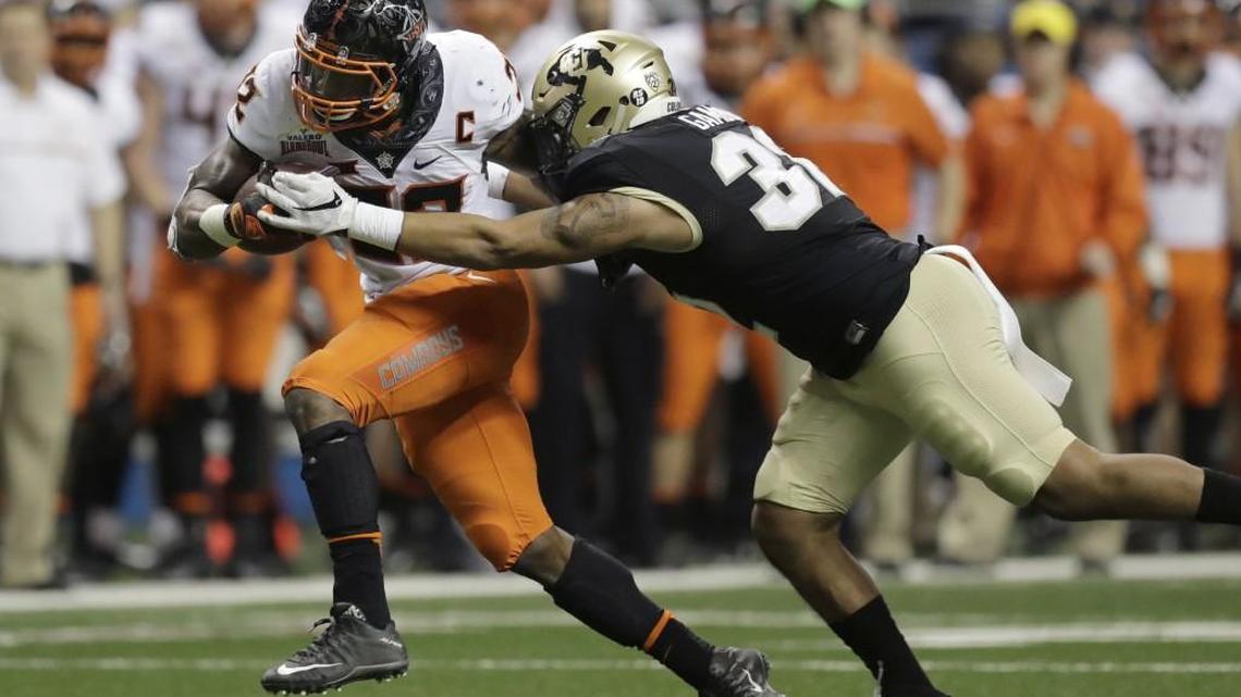 The Seahawks ended the NFL draft Saturday by selecting Oklahoma State running back Chris Carson, left, running here in December’s Alamo Bowl against Colorado.