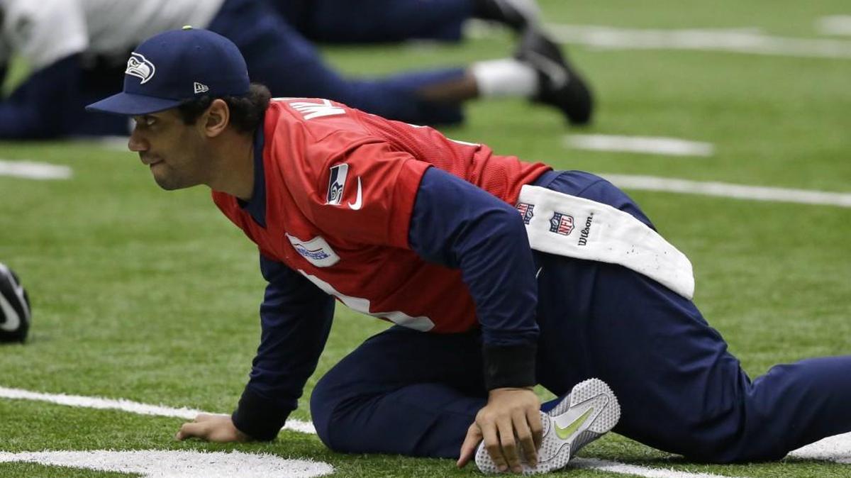 Quarterback Russell Wilson, without the brace on his previously injured left knee any longer, stretches at the start of practice Tuesday at Seahawks headquarters in Renton. Saturday’s NFC divisional playoff game at Atlanta will be Wilson’s 92nd consecutive start to begin his career.