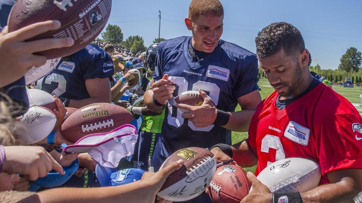 Seahawks tight end Jimmy Graham, left, and quarterback Russell Wilson sign autographs last month at camp. “For me? Less hits. Longer career,” Graham says of Seattle’s run-based schemes.