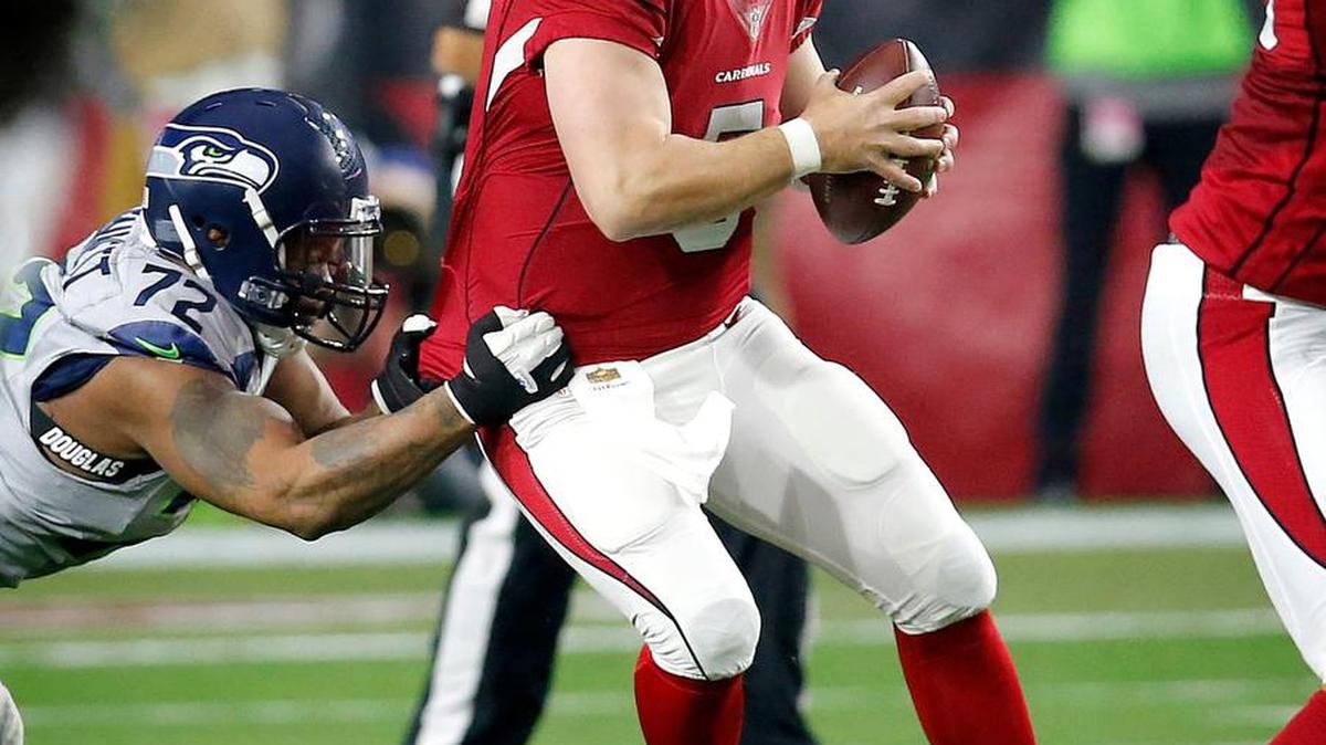 Arizona’s backup quarterback, Drew Stanton, is pulled down by Seattle’s Michael Bennett in the second half Sunday. Bennett had a career-high 10 sacks this season.