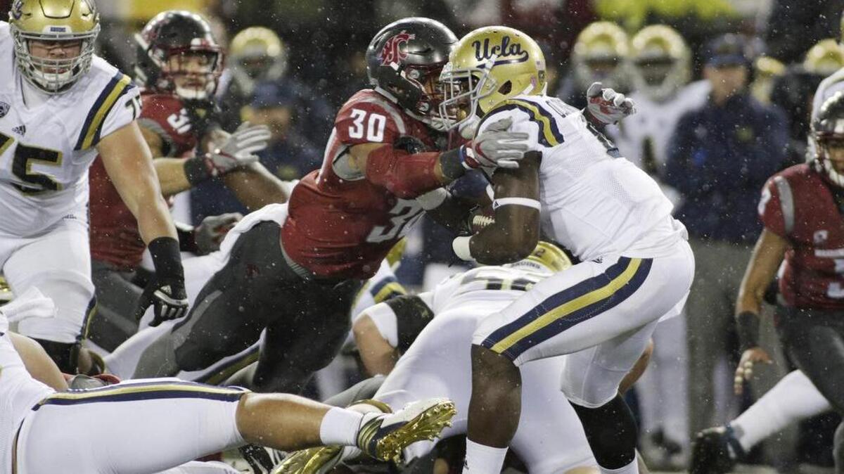 Washington State defensive lineman Nnamdi Oguayo (30) brings down UCLA running back Bolu Olorunfunmi (4) during a 27-21 victory over the Bruins on Saturday, the Cougars’ fourth straight win.
