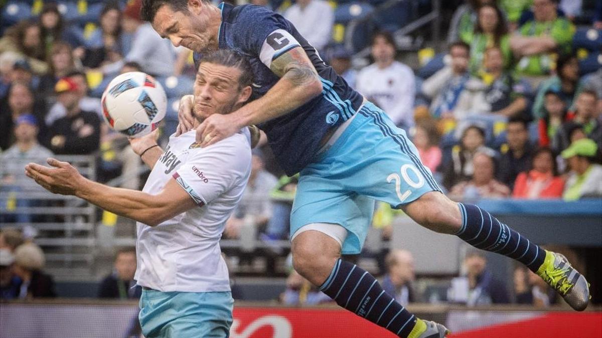 Sounders' Zach Scott, top, wraps himself around West Ham's Andy Carroll while battling for a loose ball at CenturyLink Field on Tuesday, July 5, 2016.