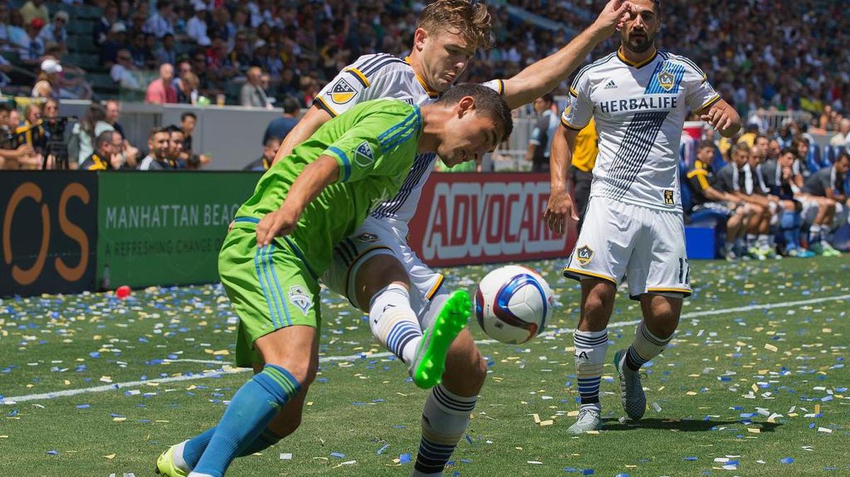 
Los Angeles Galaxy midfielder Robbie Rogers controls the ball against Seattle Sounders FC midfielder Cristian Roldan (green jersey) on Sunday at the StubHub Center in Carson, Calif.
