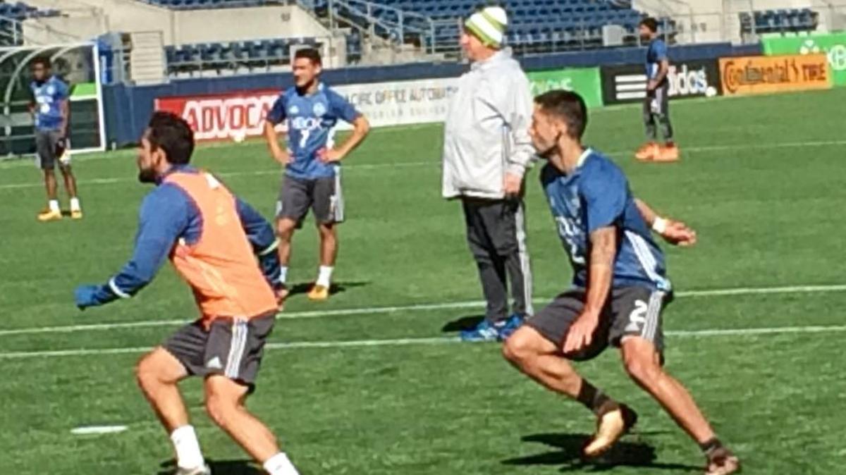 Herculez Gomez (left) defends Clint Dempsey on a corner kick as coach Sigi Schmid looks on during Seattle Sounders training Thursday at CenturyLink Field.