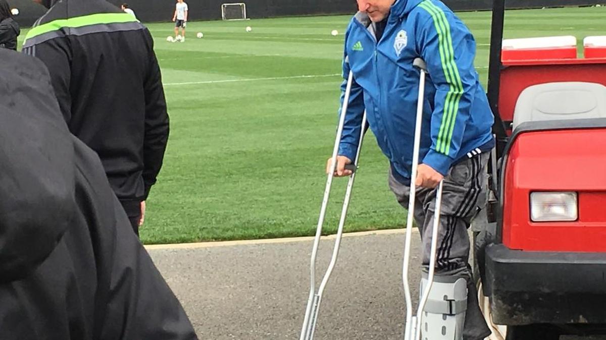 Sigi Schmid on crutches at training today after breaking fibula in slip at home.