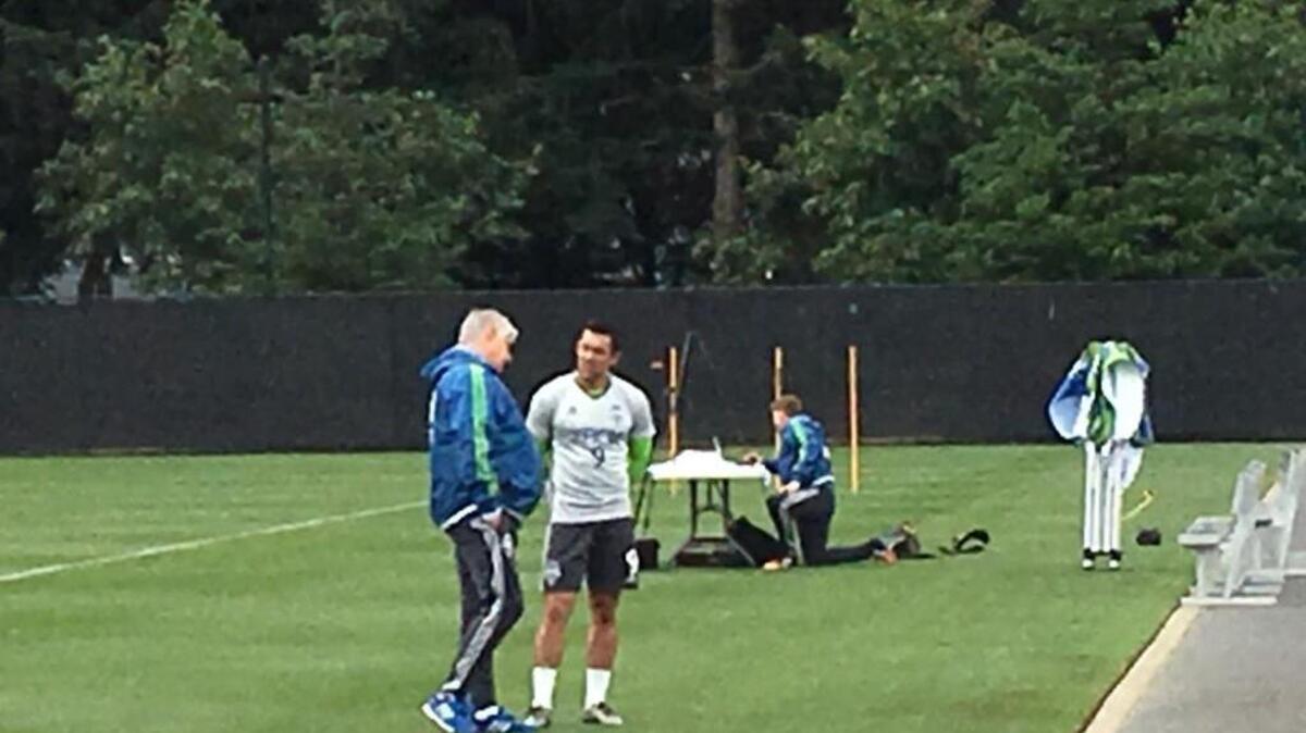 Seattle Sounders coach Sigi Schmid talks with forward Herculez Gomez after Thursday training.