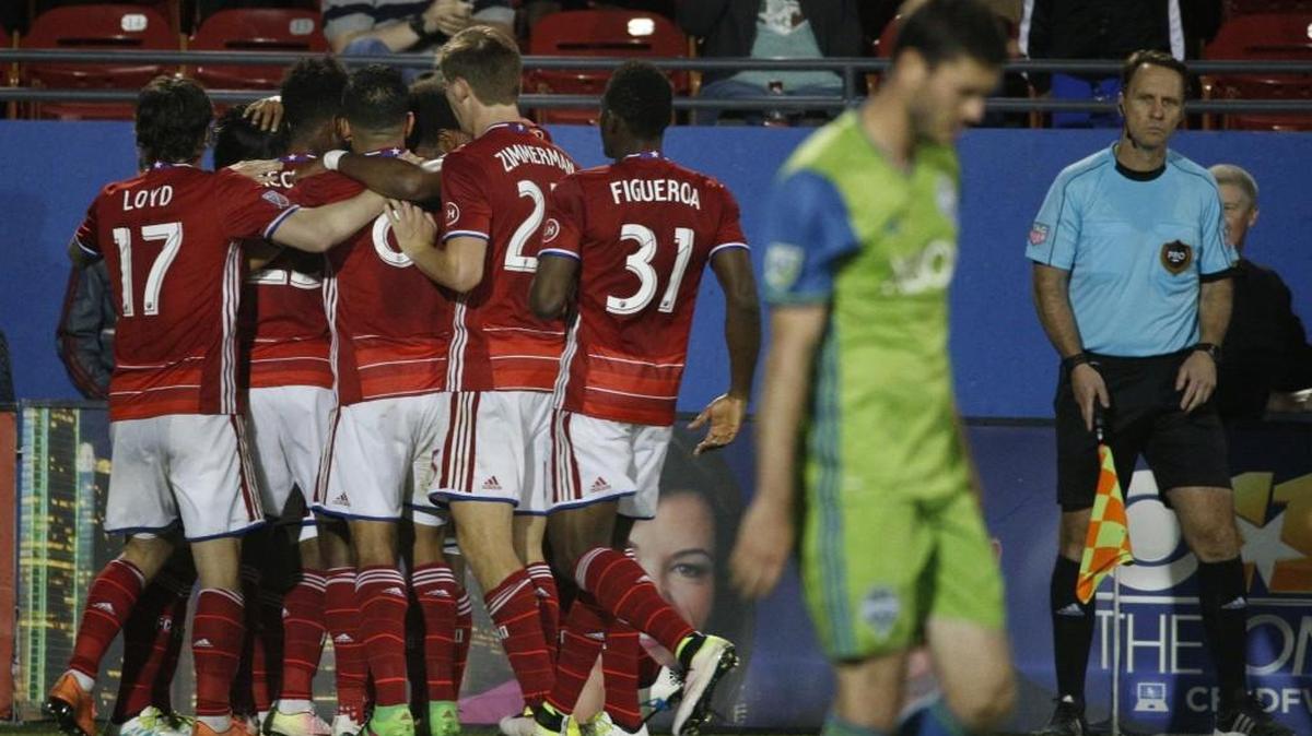 Seattle Sounders captain Brad Evans contrasts with FC Dallas celebration after goal Saturday, in Frisco, Texas.