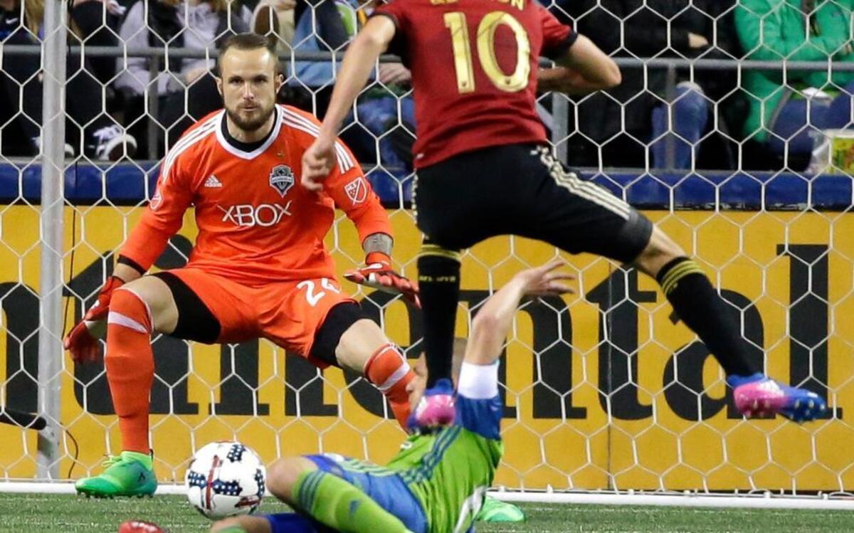 Seattle Sounders goalkeeper Stefan Frei, upper left, position to stop a shot by Atlanta United midfielder Miguel Almiron (10) as Almiron leaps over Sounders' Osvaldo Alonso in the second half of an MLS soccer match, Friday, March 31, 2017, in Seattle. The match ended in a 0-0 tie.