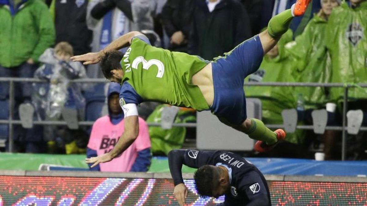 Seattle Sounders defender Brad Evans (3) falls over Sporting Kansas City forward Dom Dwyer after Evans went up for a header in the second half of an MLS soccer match, Sunday, March 6, 2016, in Seattle. Evans landed hard on his shoulder and left the match injured. Sporting Kansas City beat the Sounders 1-0. (AP Photo/Ted S. Warren)