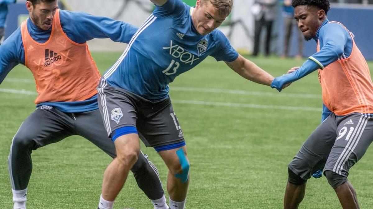 Jordan Morris of the Seattle Sounders is surrounded by "opponenets" Brad Evans (left) and Oniel Fisher (right) in a soccer practice session at Century Link Field in Seattle, February 22, 2016.