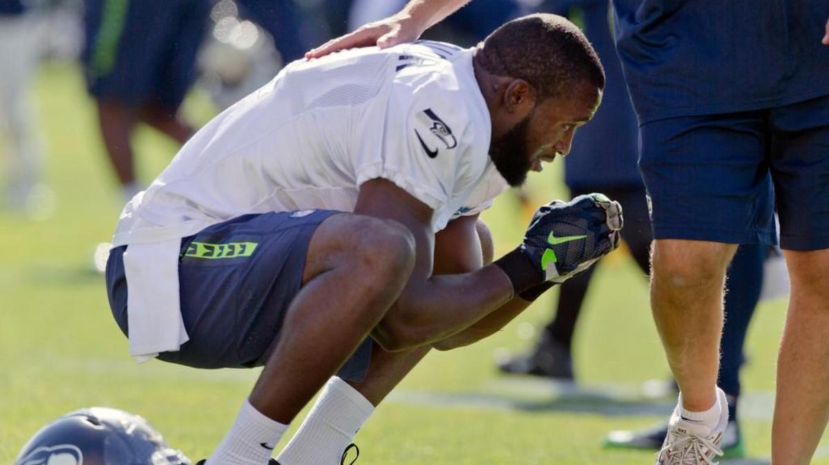
Seahawks safety Kam Chancellor is patted on the back by a staff member while on the practice field for the first time after ending his hold out Wednesday.
