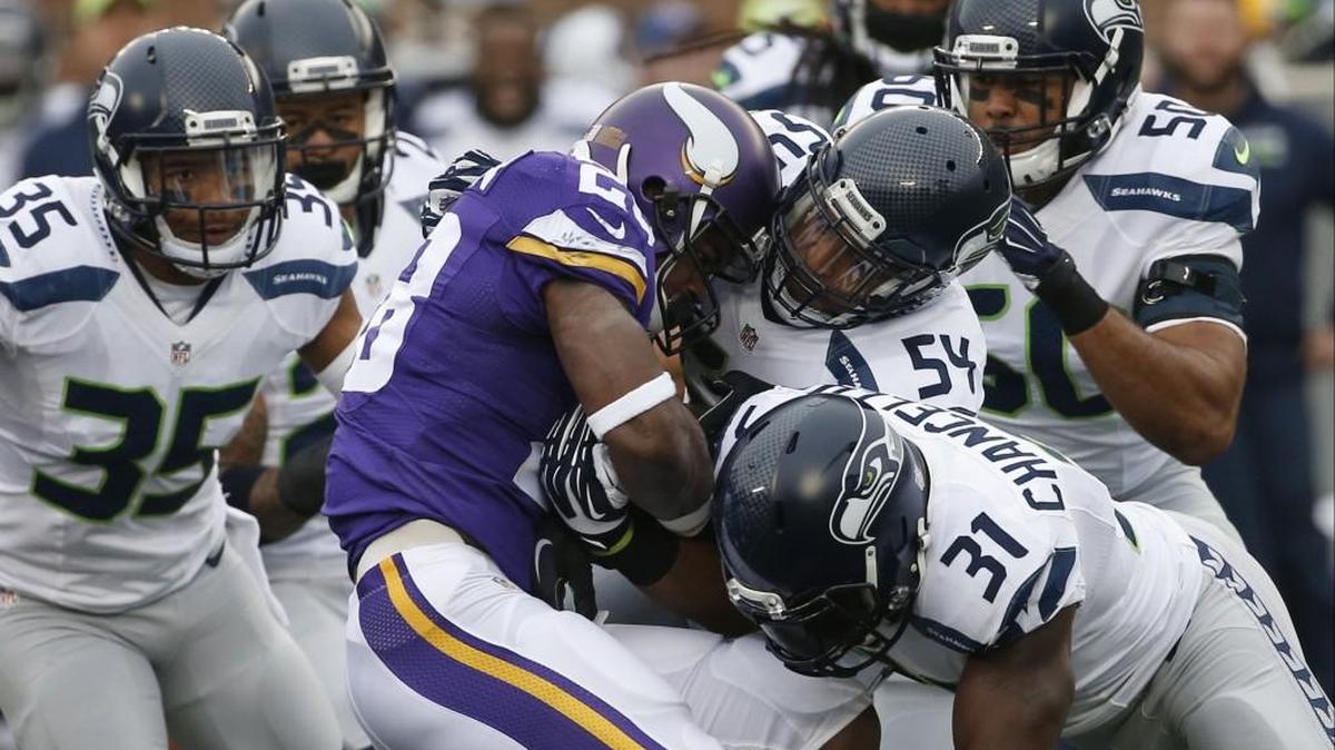 Vikings running back Adrian Peterson (28) is stopped by Seahawks defenders including linebacker Bobby Wagner (54) and strong safety Kam Chancellor (31) in Seattle’s 38-7 win at Minnesota on Dec. 6.