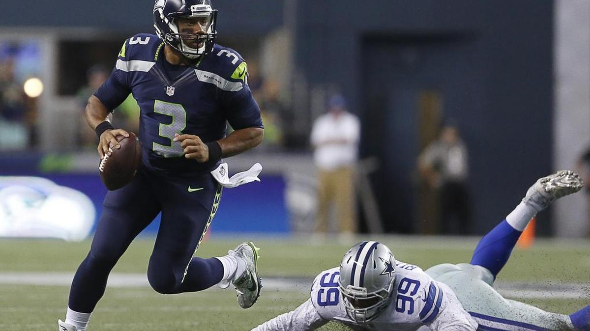 Seahawks quarterback Russell Wilson dodges Dallas Cowboys defender Ryan Russell before throwing a touchdown to Tyler Lockett in the third quarter.