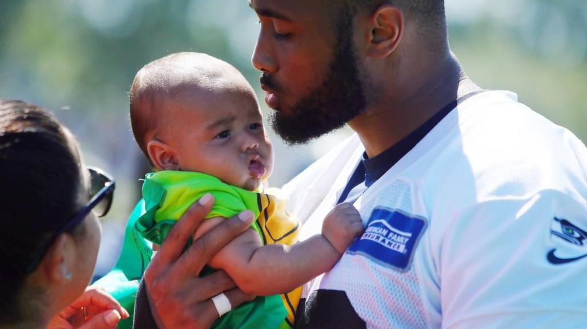 K.J. Wright holds his 3-month-old son after a Seahawks practice on Aug. 16.