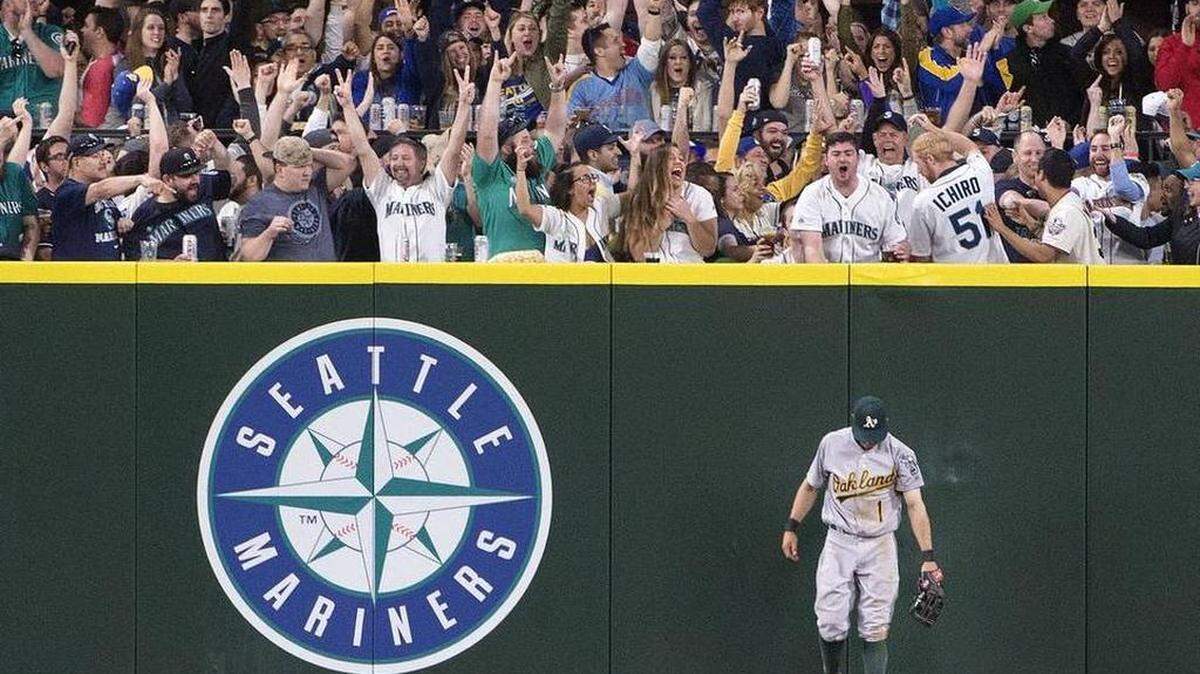 Seattle fans roar their approval after new Mariner Dae-Ho Lee hit a homer in the fifth inning that Oakland outfielder Billy Burns couldn't get to. Photo taken at Safeco Field in Seattle on Friday, April 8, 2016.