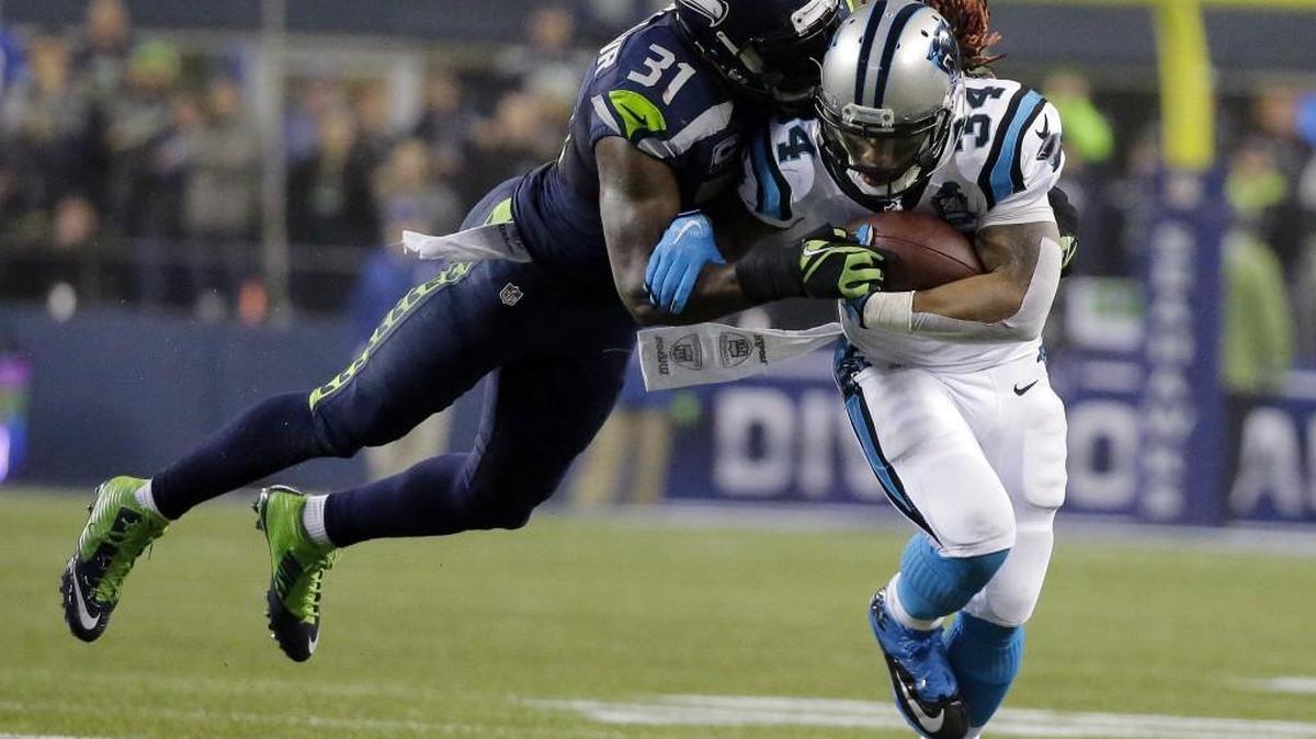 Seahawks safety Kam Chancellor, left, dives to tackle Panthers running back DeAngelo Williams during an NFC divisional playoff game on Jan. 10, 2015.