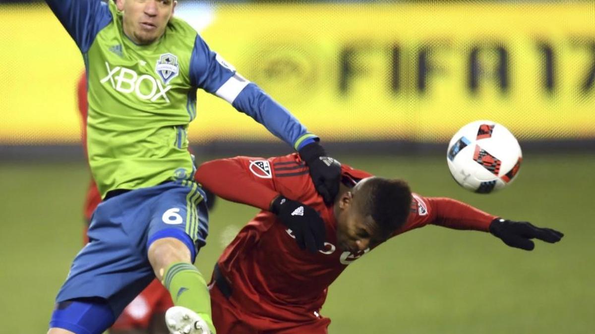 Sounders midfielder Osvaldo Alonso, left, and Toronto FC midfielder Armando Cooper battle for the ball during the MLS Cup final. Alonso played for 120 minutes in Seattle’s win despite suffering from a badly sprained knee.