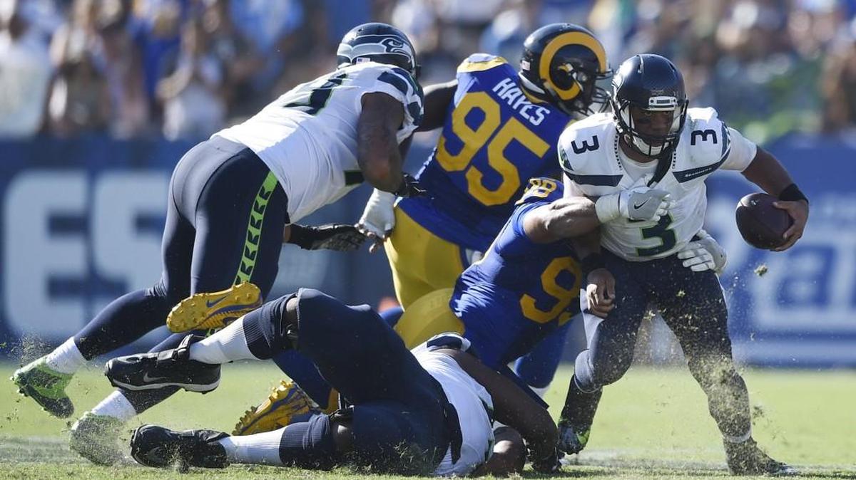 Seattle Seahawks quarterback Russell Wilson (3) scrambles while under pressure by Los Angeles Rams defensive tackle Aaron Donald (99) during the second half of an NFL football game at the Los Angeles Memorial Coliseum, Sunday, Sept. 18, 2016, in Los Angeles.