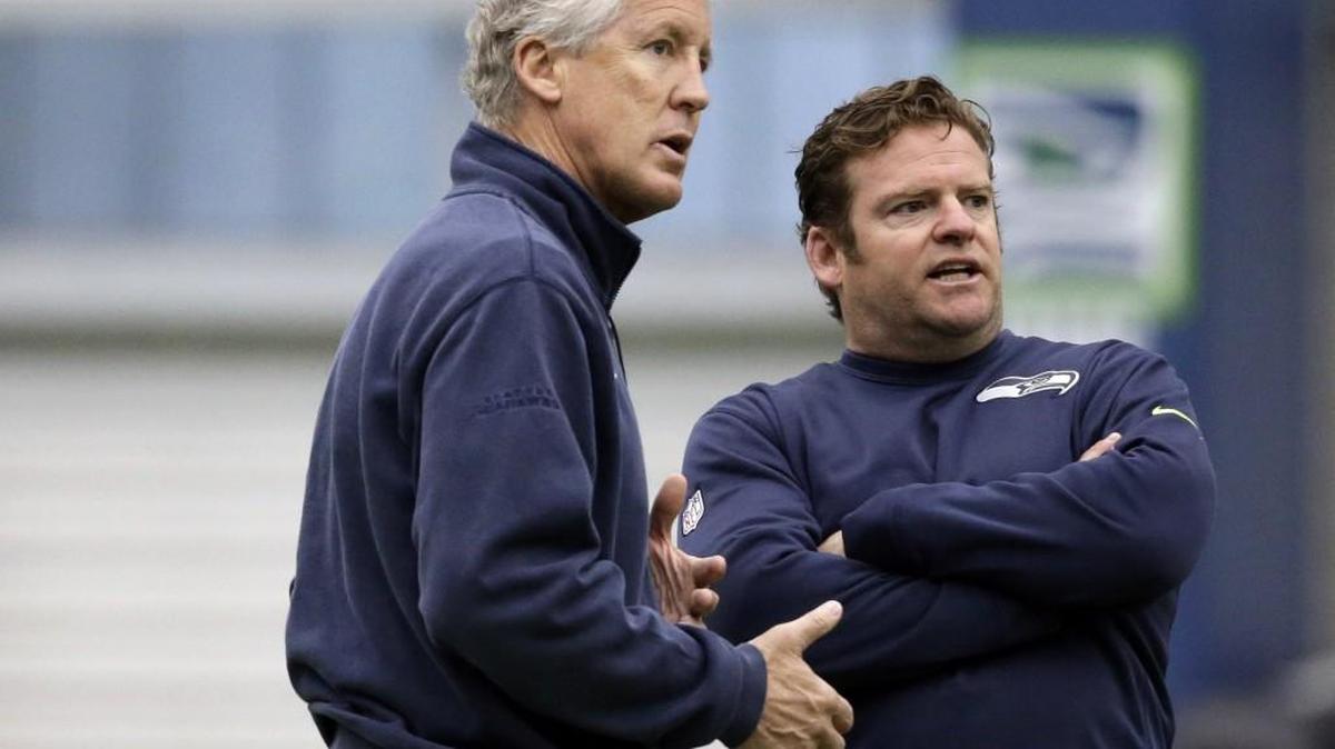 Seattle Seahawks head coach Pete Carroll, left, and general manager John Schneider talk during an NFL football rookie minicamp workout.