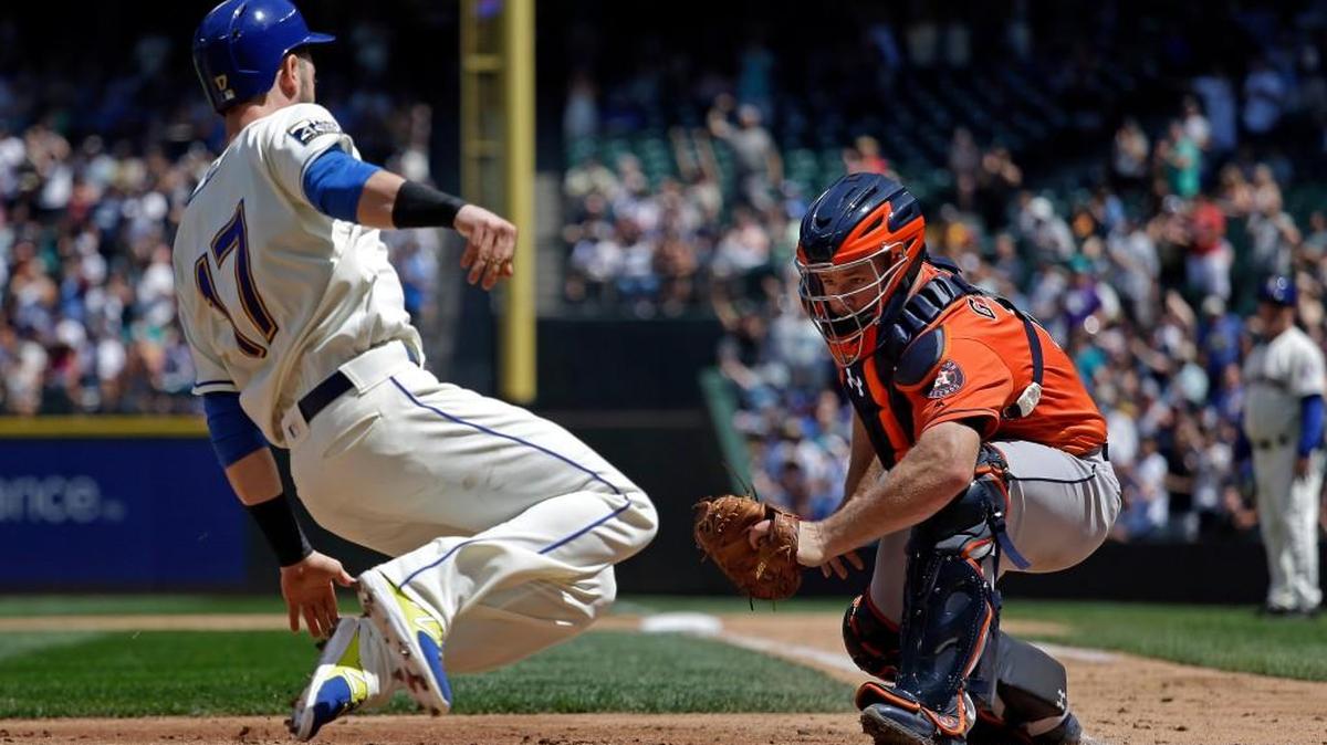 Seattle’s Mitch Haniger (17) slides toward a tag by Houston catcher Evan Gattis on Sunday in the second inning in Seattle. Haniger was called out.