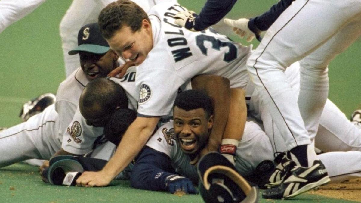 Seattle Mariners’ Ken Griffey Jr. smiles from beneath a pile of teammates who mobbed him after he scored the winning run in the bottom of the 11th inning of a baseball game against the New York Yankees in Seattle.