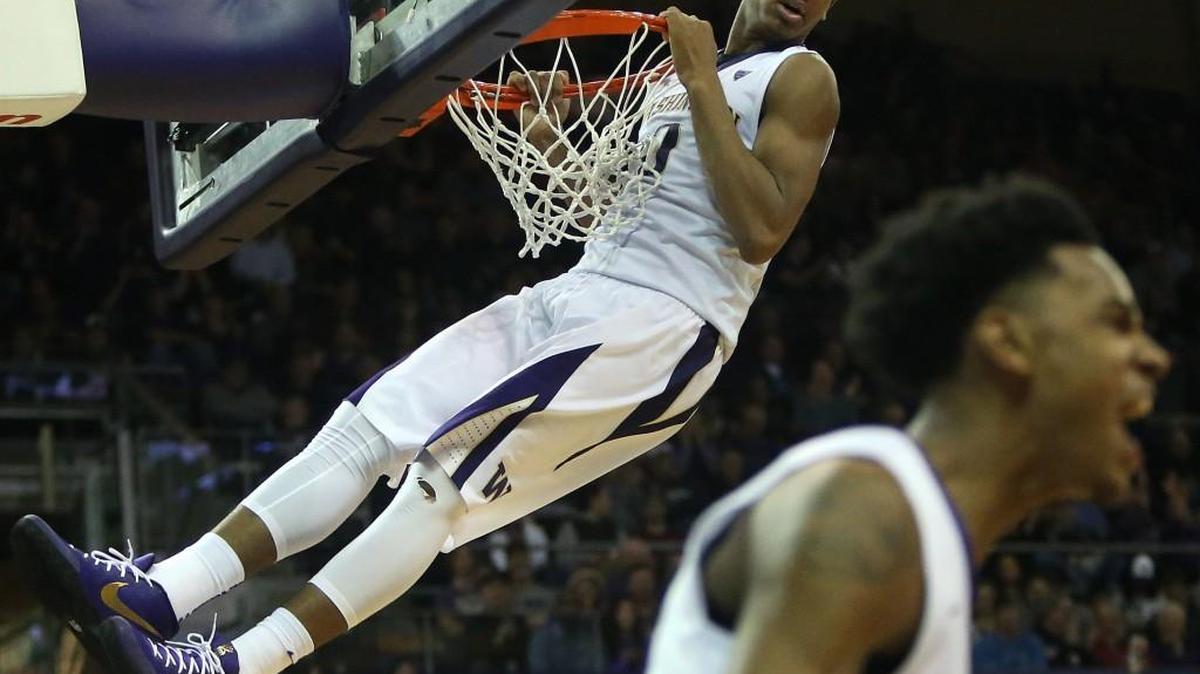 Washington’s Marquese Chriss hangs onto the basket after dunking against Montana. Chriss would receive a technical foul for the chin-above-the-rim dunk.