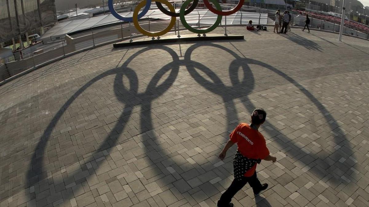 A worker walks past a set of Olympic rings in the Olympic Park ahead of the 2016 Summer Olympics, in Rio de Janeiro.