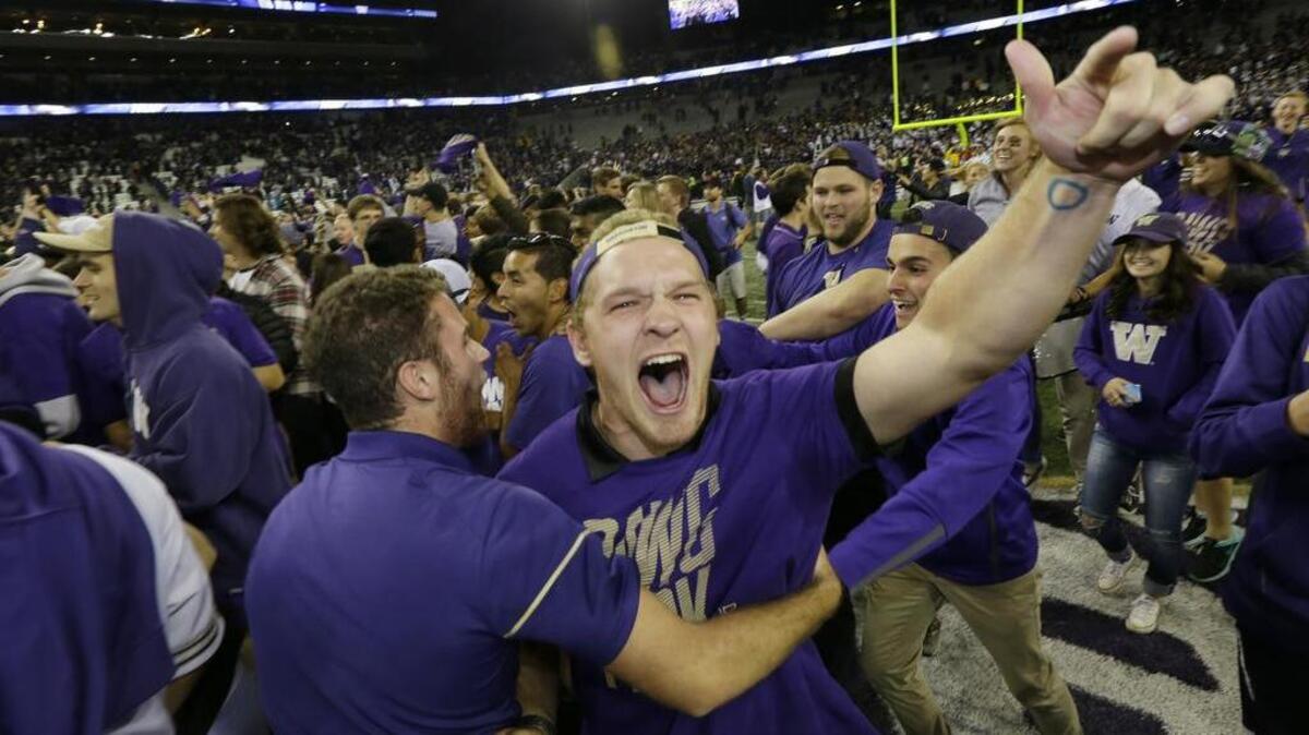 Huskies fans rush the field after No. 10 Washington routed No. 7 Stanford, 44-6, at Husky Stadium in Seattle on Friday night.