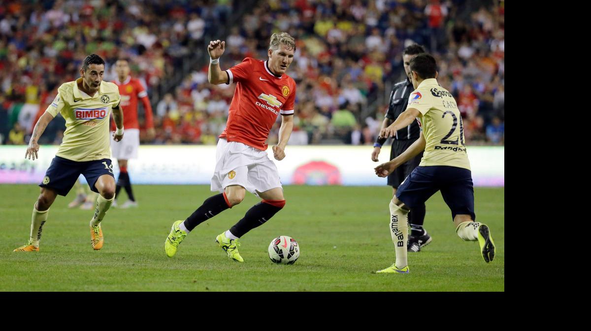 
Manchester United's Bastian Schweinsteiger, center, moves the ball through the defense of Club America's Francisco Rivera, right, and Rubens Sambueza, left, on Friday in Seattle.
